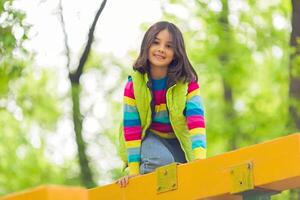 Portrait of a cute little girl on a bright wooden platform in the park in spring photo