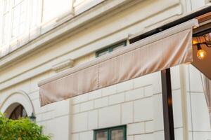 Modern beige awning on city shop to promote shop logo. Stylish urban advertising solution for branding and storefront visibility photo