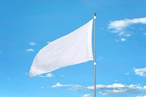 White flag fluttering in the wind on a sunny day. Ideal for mockups, adding designs, or national flags. Clear blue sky in the background photo