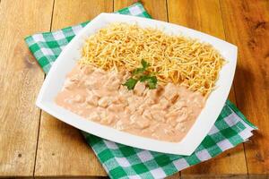 Homemade chicken stroganoff in ceramic plate on red checkered tablecloth photo