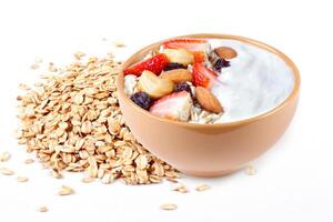 natural yogurt with oats, strawberries and nuts in ceramic bowl isolated on white background top view photo