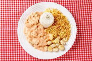 Homemade chicken stroganoff in ceramic plate on red checkered tablecloth photo