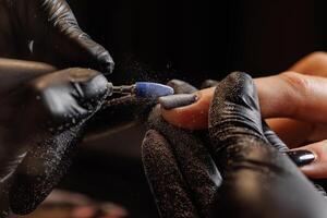 Manicurist doing hardware manicure to female client using special tools photo