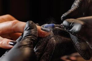 Manicurist doing hardware manicure to female client using special tools photo