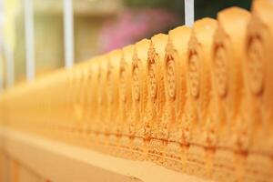 Buddhist temple wall in Orange Yellow color have pattern with beautifully carved and refined. photo
