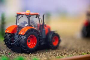 Orange toy tractor laying on the ground in the garden where the background was blurred. photo