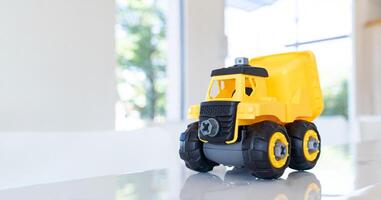 Dump truck, yellow construction toy vehicle with articulated parts built with sturdy plastic is placed on a table. photo