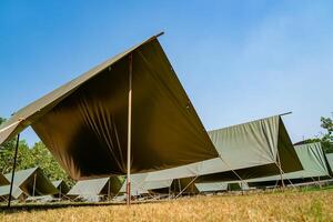 The simple and normal empty Canvas Tents in the row and column on the grass field at outdoor field in afternoon time. photo