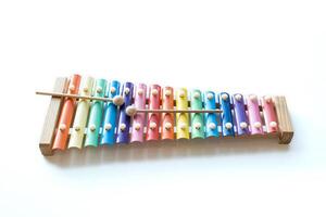 Two wooden sticks on colorful rainbow xylophone instrument toy isolated on white table background. photo