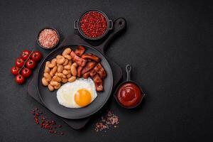 English breakfast with fried eggs, bacon, beans, tomatoes, spices and herbs photo