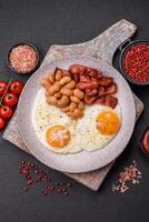 English breakfast with fried eggs, bacon, beans, tomatoes, spices and herbs photo