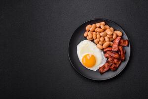 English breakfast with fried eggs, bacon, beans, tomatoes, spices and herbs photo