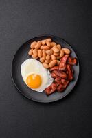 English breakfast with fried eggs, bacon, beans, tomatoes, spices and herbs photo