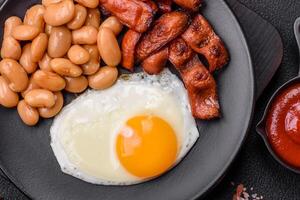 English breakfast with fried eggs, bacon, beans, tomatoes, spices and herbs photo