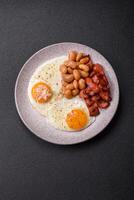 English breakfast with fried eggs, bacon, beans, tomatoes, spices and herbs photo