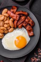 English breakfast with fried eggs, bacon, beans, tomatoes, spices and herbs photo