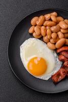 English breakfast with fried eggs, bacon, beans, tomatoes, spices and herbs photo