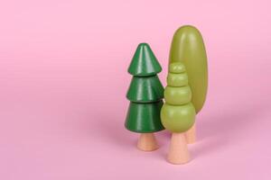 Wooden model of a tree with a green crown and trunk on a pink background photo