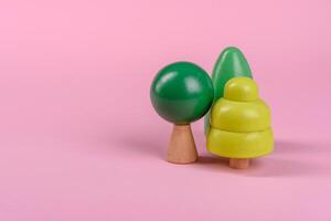 Wooden model of a tree with a green crown and trunk on a pink background photo
