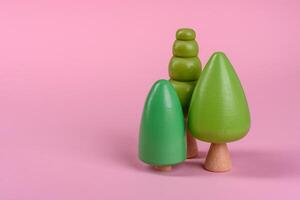 Wooden model of a tree with a green crown and trunk on a pink background photo