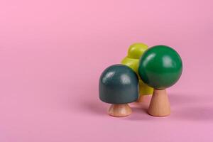 Wooden model of a tree with a green crown and trunk on a pink background photo