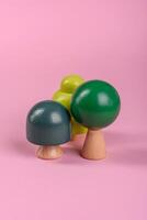 Wooden model of a tree with a green crown and trunk on a pink background photo