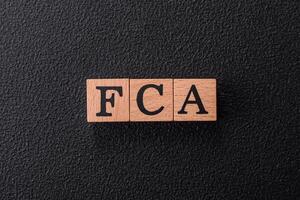 Inscription FCA wooden cubes, conceptual background with copy space photo