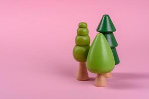 Wooden model of a tree with a green crown and trunk on a pink background photo
