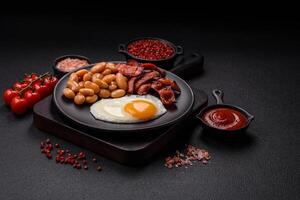 English breakfast with fried eggs, bacon, beans, tomatoes, spices and herbs photo