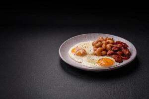 English breakfast with fried eggs, bacon, beans, tomatoes, spices and herbs photo
