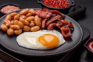 English breakfast with fried eggs, bacon, beans, tomatoes, spices and herbs photo