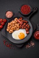 English breakfast with fried eggs, bacon, beans, tomatoes, spices and herbs photo