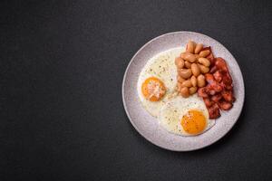 English breakfast with fried eggs, bacon, beans, tomatoes, spices and herbs photo