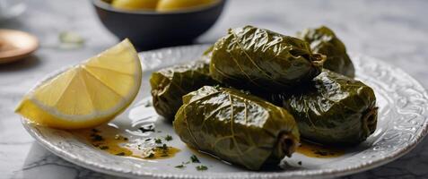 Dolma served on a white quartz background, Grape leaves stuffed with seasoned rice and herbs, Garnished with lemon wedges, turkish food. photo