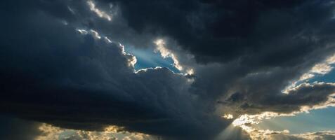 Dramatic sky with rays of light piercing through dark clouds evoking a sense of awe and the sublime beauty of nature. photo