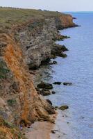 Steep rocky clay shore overgrown with steppe vegetation in eastern Crimea photo