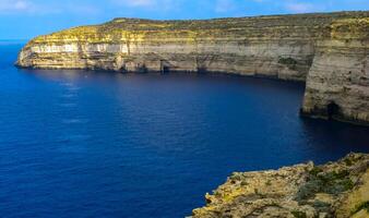 High vertical rocky shore on the island of Gozo, Malta photo