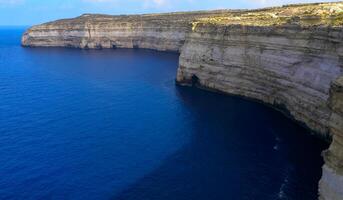High vertical rocky shore on the island of Gozo, Malta photo