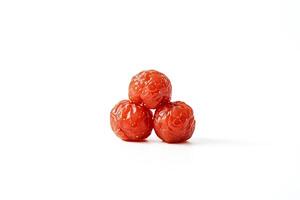 Three red candied plums arranged in a triangle on a white background photo