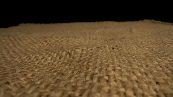 This features a close up view of the texture of burlap fabric. The camera slowly pans across the surface, revealing the intricate woven pattern of the natural fibers. video