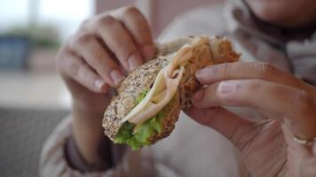 Person enjoying a nutritious sandwich filled with lettuce and turkey, a healthy meal option video