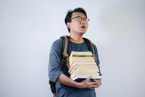 Asian young male student wearing bag and carrying a lot of books smiling and happy expression with isolated white background photo