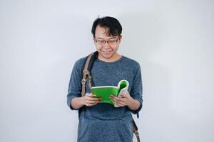 Asian young male student wearing bag and carrying books smiling and happy expression with isolated white background photo