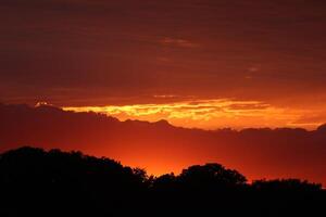 Golden sunset, dark clouds in sunrise time. Beautiful light of nature. Amazing red colors of the setting sun. Majestic clouds flowing in sunrise sky. Evening dark clouds photo