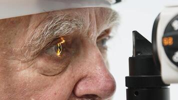 Close-up of a senior man having his vision tested on an ophthalmology diagnostic vision testing equipment. Old man doing eye test with non contact tonometer, checking vision at optical clinic photo