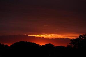 Golden sunset, dark clouds in sunrise time. Beautiful light of nature. Amazing red colors of the setting sun. Majestic clouds flowing in sunrise sky. Evening dark clouds photo