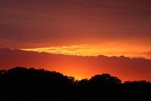 Golden sunset, dark clouds in sunrise time. Beautiful light of nature. Amazing red colors of the setting sun. Majestic clouds flowing in sunrise sky. Evening dark clouds photo