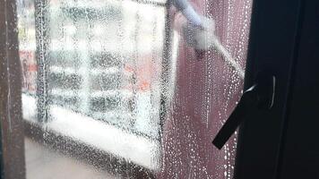 Rubber squeegee cleans a soaped window. video