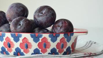 Fresh plums in a bowl on table video