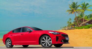 Red car on a background of palm trees. Stylish, modern, bright image of the car for design solutions. photo